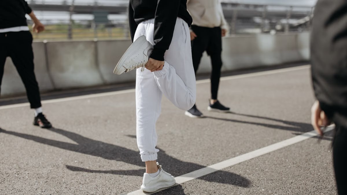 A diverse group of adults stretching and warming up on an urban road outdoors.